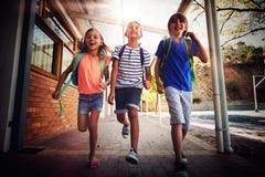 La scuola felice scherza il funzionamento in corridoio fotografia stock La scuola felice scherza il funzionamento in corridoio fotografia stock