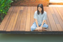 La seduta asiatica della donna si rilassa sul terrazzo o sul portico di legno vicino allo stagno nel giardino immagini stock La seduta asiatica della donna si rilassa sul terrazzo o sul portico di legno vicino allo stagno nel giardino immagini stock