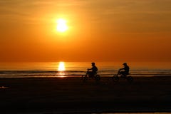 La silueta de la gente está montando una motocicleta en la puesta del sol imágenes de archivo libres de regalías La silueta de la gente está montando una motocicleta en la puesta del sol imágenes de archivo libres de regalías