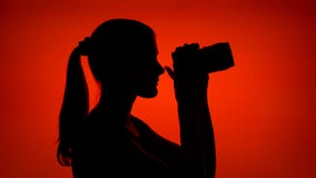 La siluetta della giovane donna messa sui trasduttori auricolari ed ascolta musica sullo Smart Phone su fondo rosso stock footage La siluetta della giovane donna messa sui trasduttori auricolari ed ascolta musica sullo Smart Phone su fondo rosso stock footage
