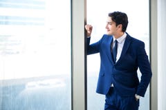 La situación hermosa joven del hombre de negocios en la ventana imagen de archivo libre de regalías La situación hermosa joven del hombre de negocios en la ventana imagen de archivo libre de regalías