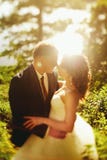 La sol hace un halo alrededor de los recienes casados que se besan en alguna parte en foto de archivo La sol hace un halo alrededor de los recienes casados que se besan en alguna parte en foto de archivo