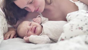 La sonrisa joven hermosa de la madre y besa a su niño recién nacido almacen de video La sonrisa joven hermosa de la madre y besa a su niño recién nacido almacen de video