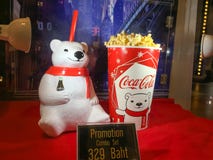 La tasse de culbuteur d'ours blanc et le seau de maïs éclaté ont placé le coke sur l'étagère au cinéma image libre de droits La tasse de culbuteur d'ours blanc et le seau de maïs éclaté ont placé le coke sur l'étagère au cinéma image libre de droits