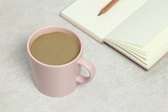 La tazza di caffè rosa, ha aperto il libro e la matita sulla struttura del granito fotografia stock La tazza di caffè rosa, ha aperto il libro e la matita sulla struttura del granito fotografia stock