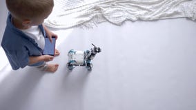 La technologie robotique futée, petit garçon d'enfant est jouée par les jouets modernes sur le smartphone de utilisation à téléco La technologie robotique futée, petit garçon d'enfant est jouée par les jouets modernes sur le smartphone de utilisation à téléco