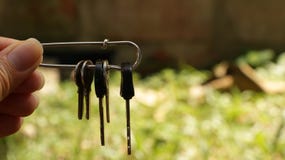 La tenuta femminile della mano digita la spilla di sicurezza fotografia stock La tenuta femminile della mano digita la spilla di sicurezza fotografia stock