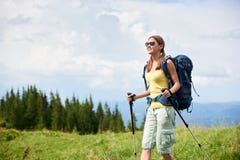 La viandante della donna che fa un'escursione sulla collina erbosa, zaino d'uso, facendo uso del trekking attacca nelle montagne immagini stock libere da diritti La viandante della donna che fa un'escursione sulla collina erbosa, zaino d'uso, facendo uso del trekking attacca nelle montagne immagini stock libere da diritti