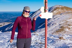 La viandante femminile che indica con il dito il percorso firma dentro le montagne dell'inverno fotografie stock La viandante femminile che indica con il dito il percorso firma dentro le montagne dell'inverno fotografie stock