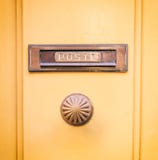La vieux boîte et bouton de lettre en laiton de courrier sur un jaune ont peint l'entrée principale, courrier des textes photo stock La vieux boîte et bouton de lettre en laiton de courrier sur un jaune ont peint l'entrée principale, courrier des textes photo stock