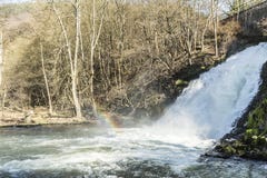 La vista de una cascada con un arco iris reflejó en el agua con una vegetación árida en el fondo en la pequeña ciudad del balnear fotografía de archivo libre de regalías La vista de una cascada con un arco iris reflejó en el agua con una vegetación árida en el fondo en la pequeña ciudad del balnear fotografía de archivo libre de regalías