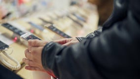 La vista del primo piano di un ` s del giovane passa la scelta del telefono cellulare nuovo in un negozio Sta provando come funzi archivi video La vista del primo piano di un ` s del giovane passa la scelta del telefono cellulare nuovo in un negozio Sta provando come funzi archivi video