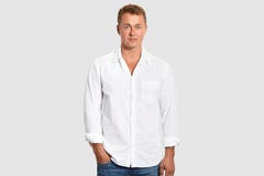 La vita sul colpo dell'imprenditore maschio attraente porta la camicia bianca ed i jeans, tengono la mano in tasca, isolata sopra fotografia stock libera da diritti La vita sul colpo dell'imprenditore maschio attraente porta la camicia bianca ed i jeans, tengono la mano in tasca, isolata sopra fotografia stock libera da diritti