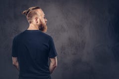 La vue arrière d'un homme barbu roux s'est habillée dans un T-shirt noir D'isolement sur le fond texturisé foncé photos stock La vue arrière d'un homme barbu roux s'est habillée dans un T-shirt noir D'isolement sur le fond texturisé foncé photos stock