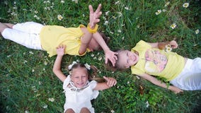 La vue d'en haut, des enfants se trouvent sur l'herbe, pré de camomille, et étirent leurs mains vers le haut Ils ont l'amusement clips vidéos La vue d'en haut, des enfants se trouvent sur l'herbe, pré de camomille, et étirent leurs mains vers le haut Ils ont l'amusement clips vidéos