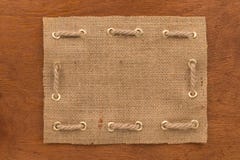 La vue faite de toile de jute avec une corde a fileté en anneaux d'or, mensonge sur une surface en bois photo stock La vue faite de toile de jute avec une corde a fileté en anneaux d'or, mensonge sur une surface en bois photo stock