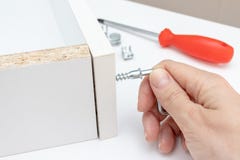 La vue haute ?troite d'une personne assemblant le nouveau tiroir blanc utilisant un tournevis, serrent une vis avec une cl? d'All image stock La vue haute ?troite d'une personne assemblant le nouveau tiroir blanc utilisant un tournevis, serrent une vis avec une cl? d'All image stock