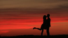La vue intégrale des couples silhouette doucement des baisers au-dessus du ciel rouge pendant le coucher du soleil L'atmosphère r banque de vidéos La vue intégrale des couples silhouette doucement des baisers au-dessus du ciel rouge pendant le coucher du soleil L'atmosphère r banque de vidéos