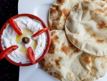 Labneh en tomaten Hoogste mening van een kom labneh, heerlijke en romige yoghurtonderdompeling met vlak brood Het voedsel van het royalty-vrije stock afbeeldingen Labneh en tomaten Hoogste mening van een kom labneh, heerlijke en romige yoghurtonderdompeling met vlak brood Het voedsel van het royalty-vrije stock afbeeldingen