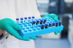 Laboratory scientist holds a plastic box with samples of transparent liquid in the vials. Stock Photos Laboratory scientist holds a plastic box with samples of transparent liquid in the vials. Stock Photos