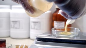 Laboratory worker working with scales. Close-up of chemist wearing gloves from can of puts quicksand on glass cup for stock photos Laboratory worker working with scales. Close-up of chemist wearing gloves from can of puts quicksand on glass cup for stock photos
