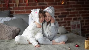 Lachende Geschwister im Bett an den Weihnachts-, Bruder- und Schwesterumarmungen auf Weihnachtsmorgen