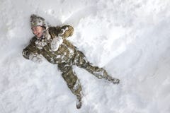 Lachende jongen die in de sneeuw leggen stock fotografie Lachende jongen die in de sneeuw leggen stock fotografie