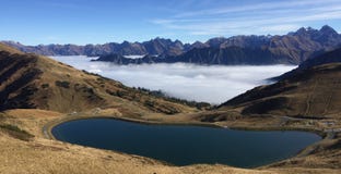 Lago mountain con le montagne e la nebbia nei precedenti immagine stock Lago mountain con le montagne e la nebbia nei precedenti immagine stock