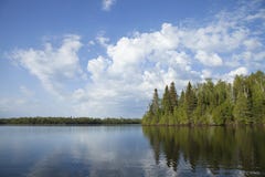 Lago septentrional minnesota con los árboles a lo largo de la orilla y las nubes brillantes en una mañana tranquila fotografía de archivo libre de regalías Lago septentrional minnesota con los árboles a lo largo de la orilla y las nubes brillantes en una mañana tranquila fotografía de archivo libre de regalías