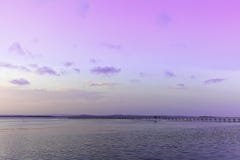 Lake landscape with long jetty by violet sky at dusk