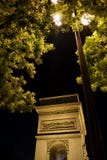 Lampost в деревьях вечером с Триумфальной Аркой осветило Париж, Францию стоковые фотографии rf Lampost в деревьях вечером с Триумфальной Аркой осветило Париж, Францию стоковые фотографии rf