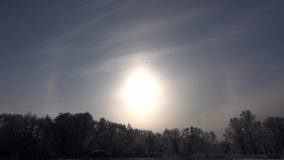 Landscape of beach and frozen river at wintertime at a frosty day with shining sun halos