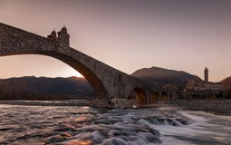 Landscape Of A Medieval Bridge Over A Turbulent River At Sunset Royalty Free Stock Image