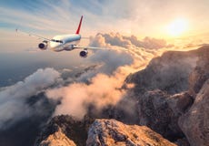 Landskap med vit passagerareflygplan-, berg-, havs- och apelsinhimmel arkivfoto Landskap med vit passagerareflygplan-, berg-, havs- och apelsinhimmel arkivfoto