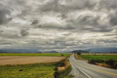 Lange wegbesnoeiingen over vallei, onder het opdoemen wolken royalty-vrije stock foto's Lange wegbesnoeiingen over vallei, onder het opdoemen wolken royalty-vrije stock foto's