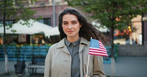 Langzaam motieportret die van mooi meisje Amerikaanse vlag houden in openlucht glimlachend stock video Langzaam motieportret die van mooi meisje Amerikaanse vlag houden in openlucht glimlachend stock video