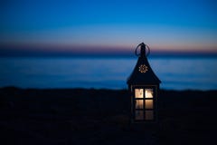 Lanterna bruciante vicino alla spiaggia, illuminazione di tramonto Lanterna su una piattaforma di legno vicino alla spiaggia al t immagini stock libere da diritti Lanterna bruciante vicino alla spiaggia, illuminazione di tramonto Lanterna su una piattaforma di legno vicino alla spiaggia al t immagini stock libere da diritti
