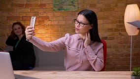 Lanzamiento del primer de la empresaria asiática adulta que toma selfies en el teléfono dentro en la oficina El usar femenino del metrajes Lanzamiento del primer de la empresaria asiática adulta que toma selfies en el teléfono dentro en la oficina El usar femenino del metrajes