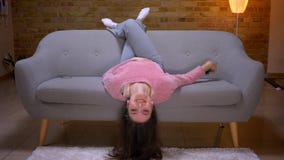 Lanzamiento del primer de la hembra caucásica morena bonita joven que ve la TV con el entusiasmo y la mentira al revés en el sofá metrajes Lanzamiento del primer de la hembra caucásica morena bonita joven que ve la TV con el entusiasmo y la mentira al revés en el sofá metrajes