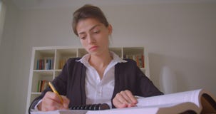 Lanzamiento del primer del estudiante caucásico bonito joven que toma las notas que miran la cámara en la biblioteca de universid metrajes Lanzamiento del primer del estudiante caucásico bonito joven que toma las notas que miran la cámara en la biblioteca de universid metrajes