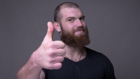 Lanzamiento del primer del hombre caucásico muscular hermoso adulto con el pulgar de la demostración de la barba encima de la son almacen de metraje de vídeo Lanzamiento del primer del hombre caucásico muscular hermoso adulto con el pulgar de la demostración de la barba encima de la son almacen de metraje de vídeo