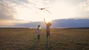 Lanzamiento feliz de la hija de la madre y del niño de la familia una cometa en prado en la puesta del sol Tiempo divertido de la almacen de video Lanzamiento feliz de la hija de la madre y del niño de la familia una cometa en prado en la puesta del sol Tiempo divertido de la almacen de video