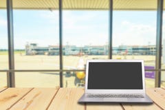 Laptop mit leerem Bildschirm auf Holztisch mit Flughafen am Torba lizenzfreie stockfotografie Laptop mit leerem Bildschirm auf Holztisch mit Flughafen am Torba lizenzfreie stockfotografie
