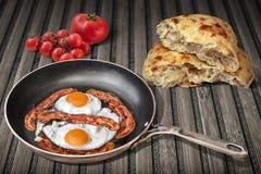 Lard et oeufs préparés dans vieux Pan Set On Rustic Bamboo faisant frire Mat With Torn Pitta Bread et groupe de Cherry Tomatoes m Photos libres de droits Lard et oeufs préparés dans vieux Pan Set On Rustic Bamboo faisant frire Mat With Torn Pitta Bread et groupe de Cherry Tomatoes m Photos libres de droits