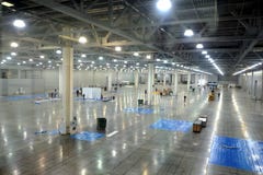 Large empty warehouse inside in industrial building with a high ceiling and artificial lighting