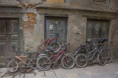 Las bicicletas lamentables viejas de diversos tamaños se colocan en la calle cerca de la pared dañada imágenes de archivo libres de regalías Las bicicletas lamentables viejas de diversos tamaños se colocan en la calle cerca de la pared dañada imágenes de archivo libres de regalías
