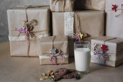 Las cajas de regalo de la Navidad adornadas con el cordón y las estrellas al lado de un vidrio de leche y de las galletas, forma imagenes de archivo Las cajas de regalo de la Navidad adornadas con el cordón y las estrellas al lado de un vidrio de leche y de las galletas, forma imagenes de archivo