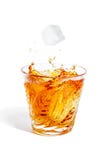 Las caídas del cubo de hielo con salpican en el vidrio con alcohol imagen de archivo Las caídas del cubo de hielo con salpican en el vidrio con alcohol imagen de archivo
