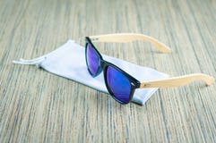 Las gafas de sol azules de moda en una cubierta del trapo son de madera en la tabla fotografía de archivo libre de regalías Las gafas de sol azules de moda en una cubierta del trapo son de madera en la tabla fotografía de archivo libre de regalías