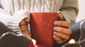 Las manos del ` s de las mujeres en suéter están sosteniendo la taza de café, de chocolate o de té caliente Comodidad del inviern foto de archivo libre de regalías Las manos del ` s de las mujeres en suéter están sosteniendo la taza de café, de chocolate o de té caliente Comodidad del inviern foto de archivo libre de regalías